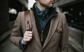 man in brown suit jacket carrying brown backpack